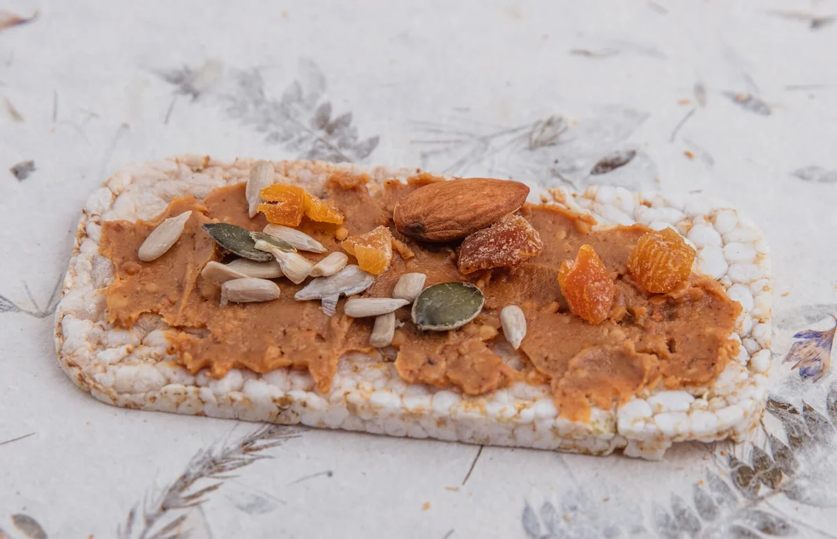 Puffed rice cake with quinoa seeds and peanut butter spread with seeds and fruits