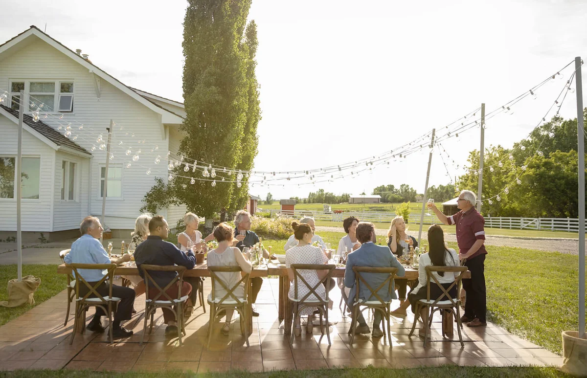 Man celebrating, toasting friends at sunny rural garden party table
