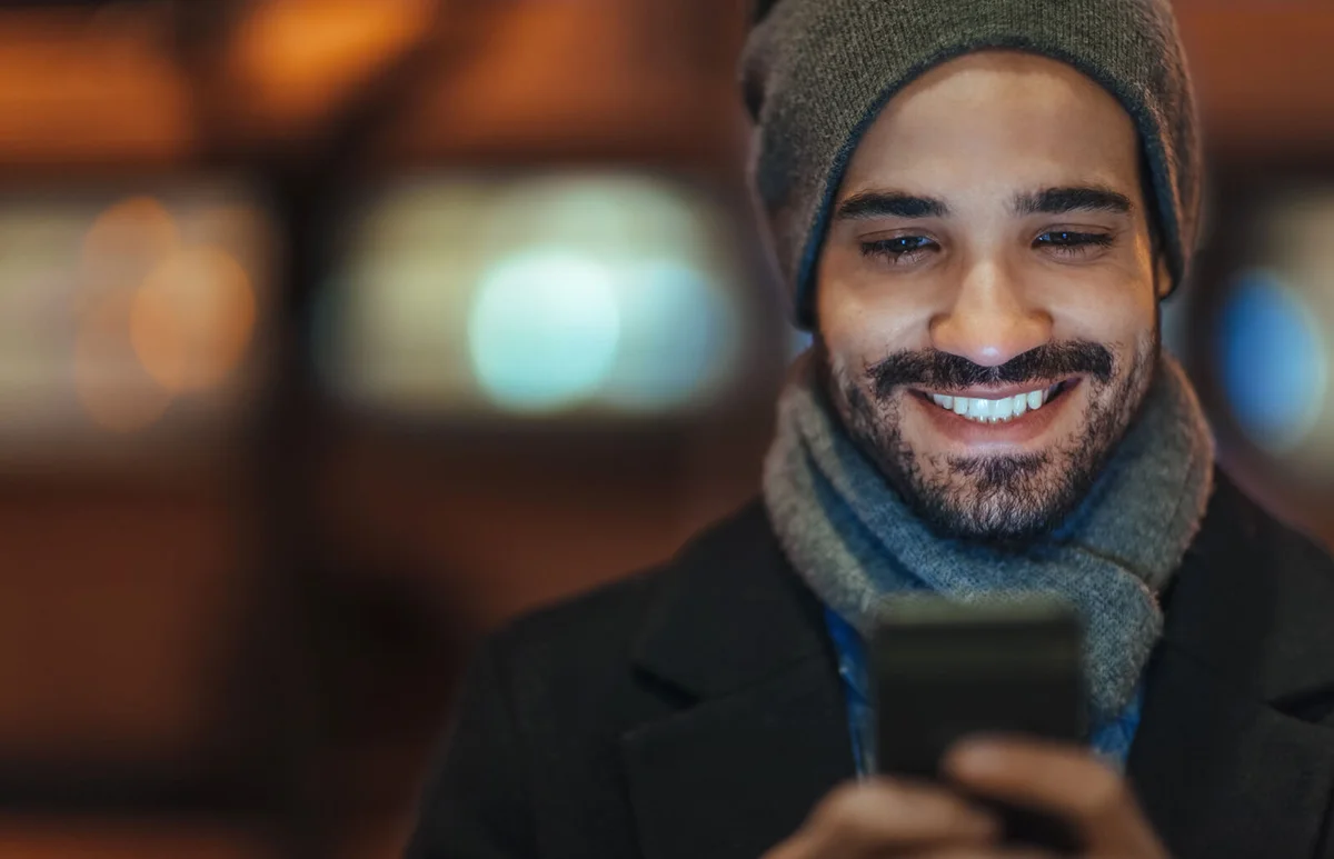 Young man using smartphone on city street at night