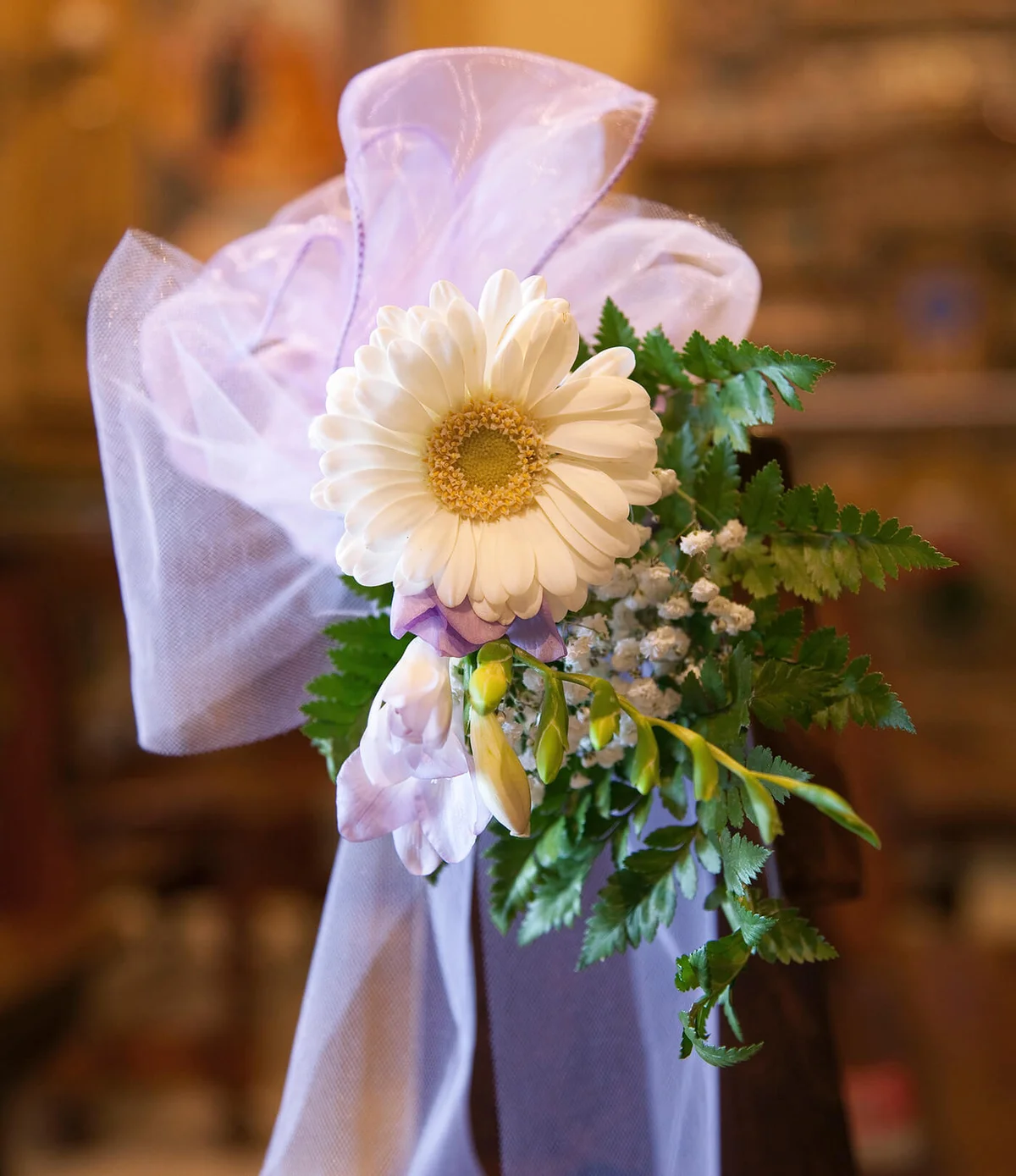 Violet bow and daisy in pew before a wedding