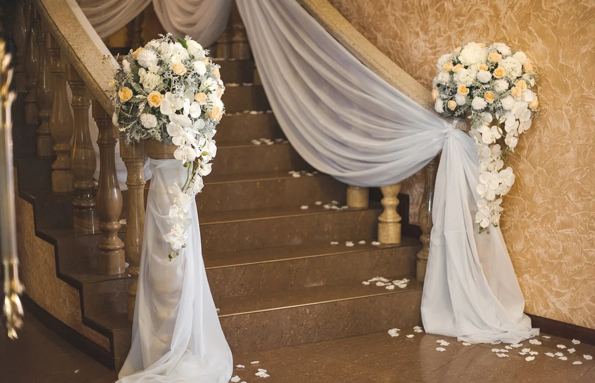 floral arrangements of roses, white orchids and soft tulle adorn marble steps