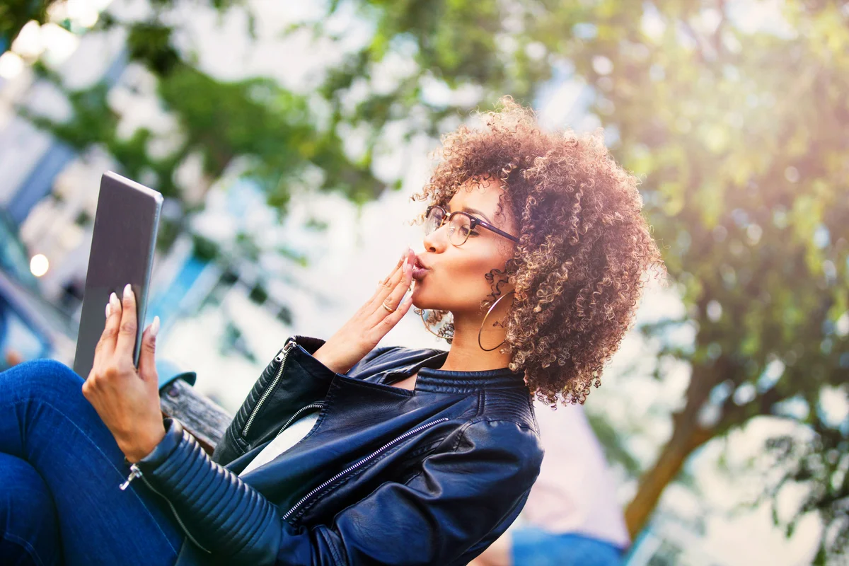 Woman using digital tablet outdoors, talking to a loved one