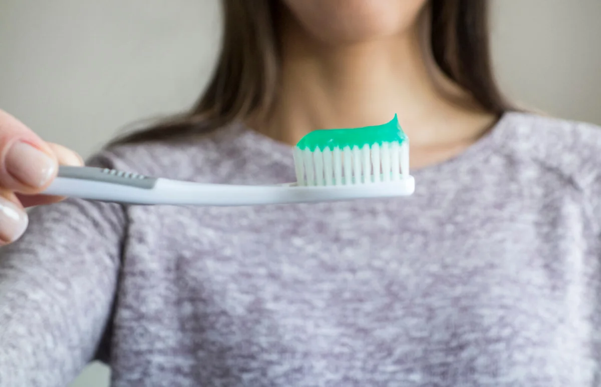 woman holding a toothbrush with toothpaste