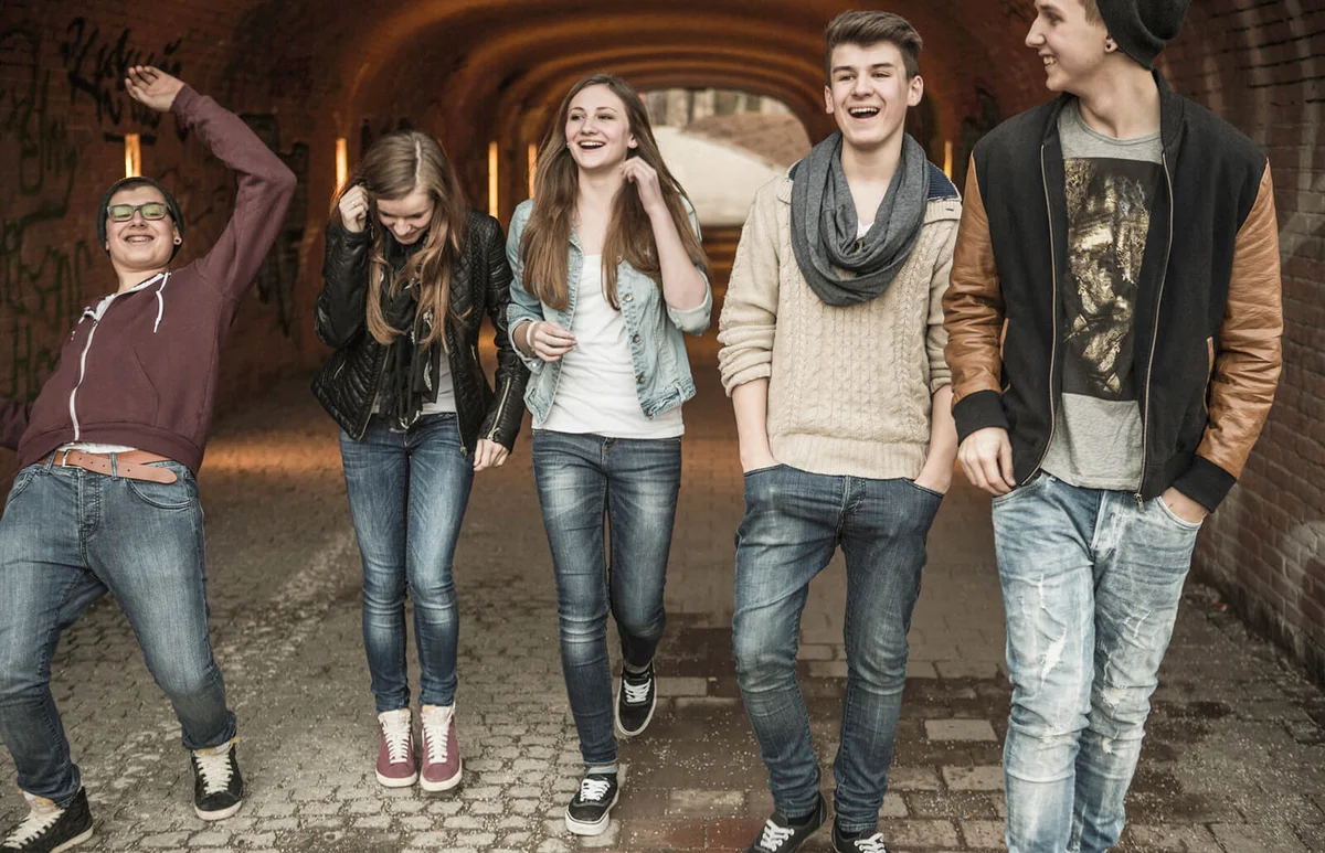Five teenagers walking through tunnel laughing and joking