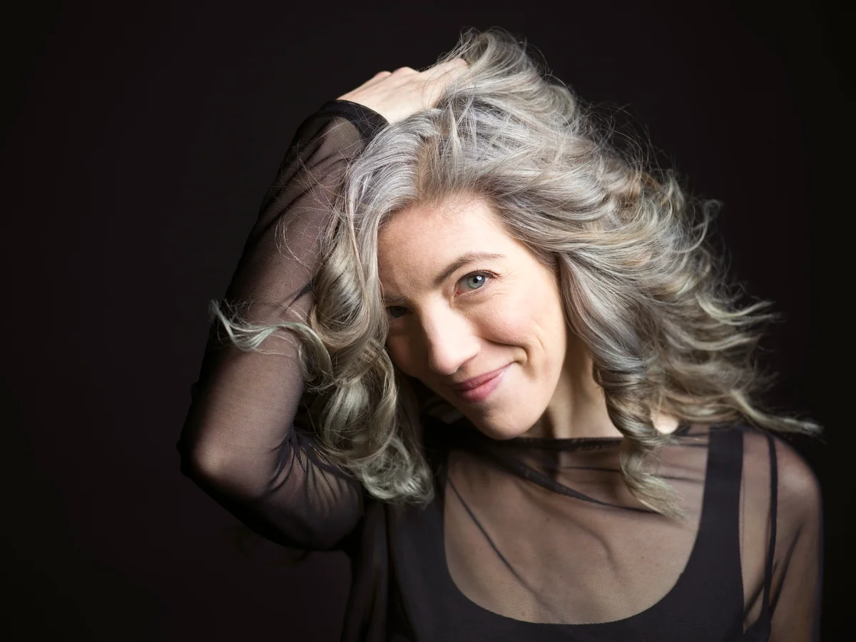 Confident woman with hand in gray hair