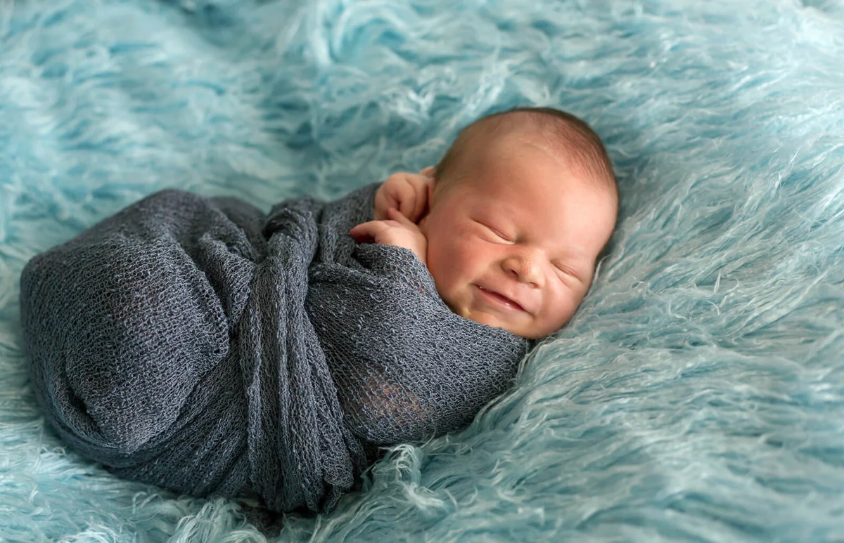 Happy smiling newborn baby in wrap