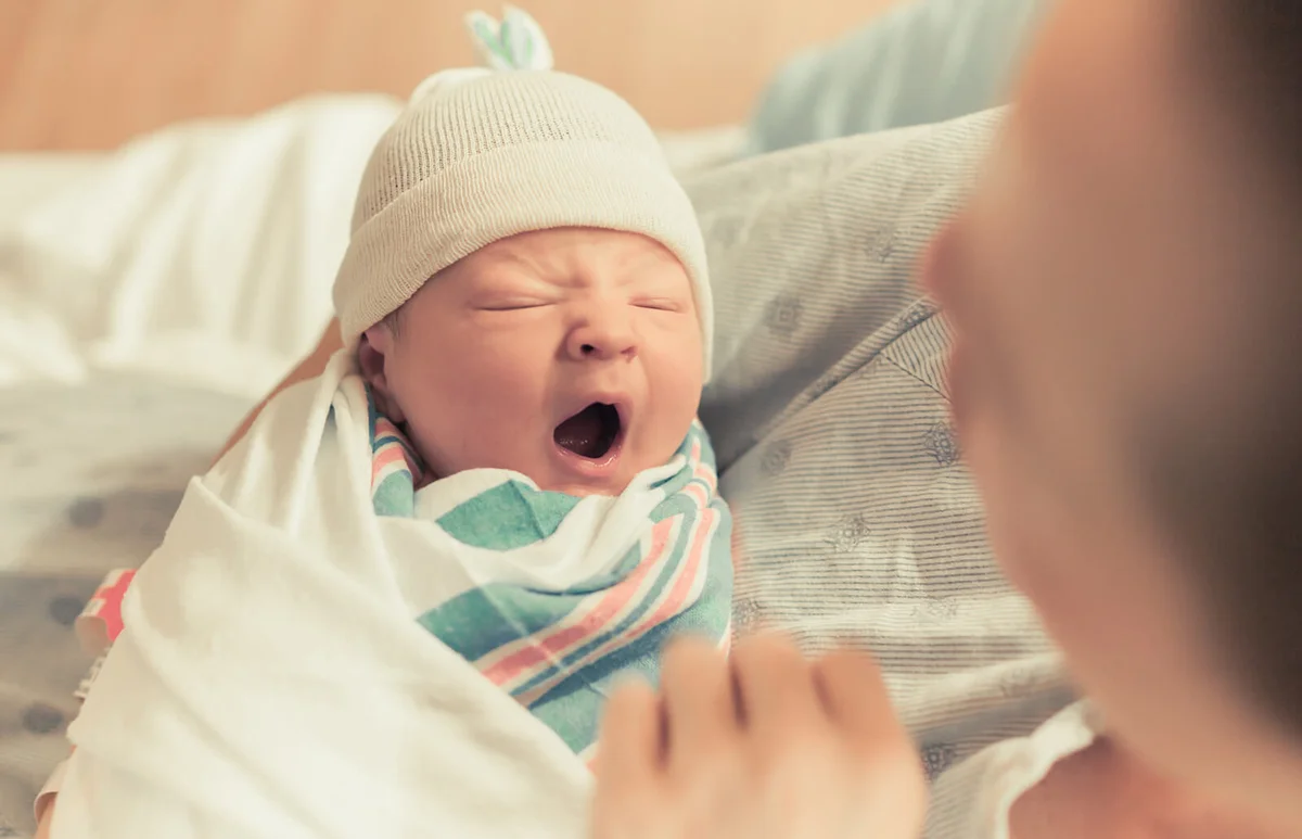 Mother holding cute newborn baby boy in here arms