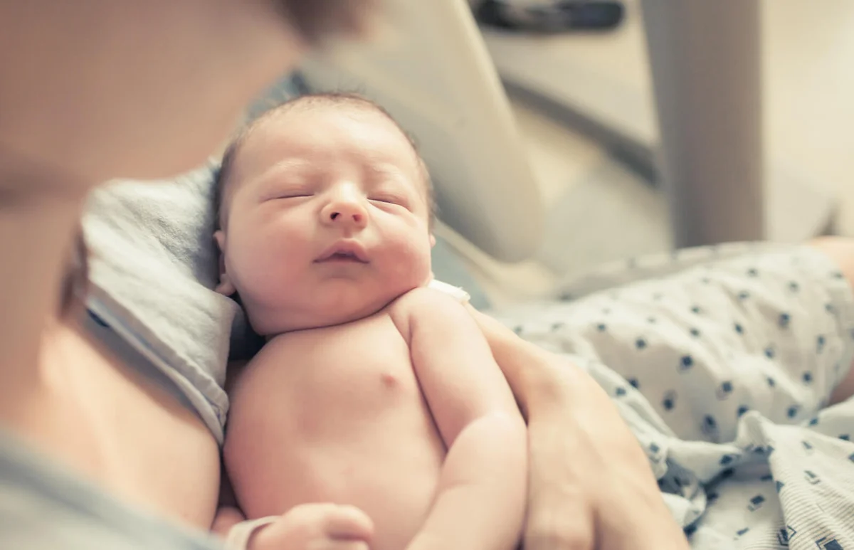 Newborn baby boy resting in mothers arms