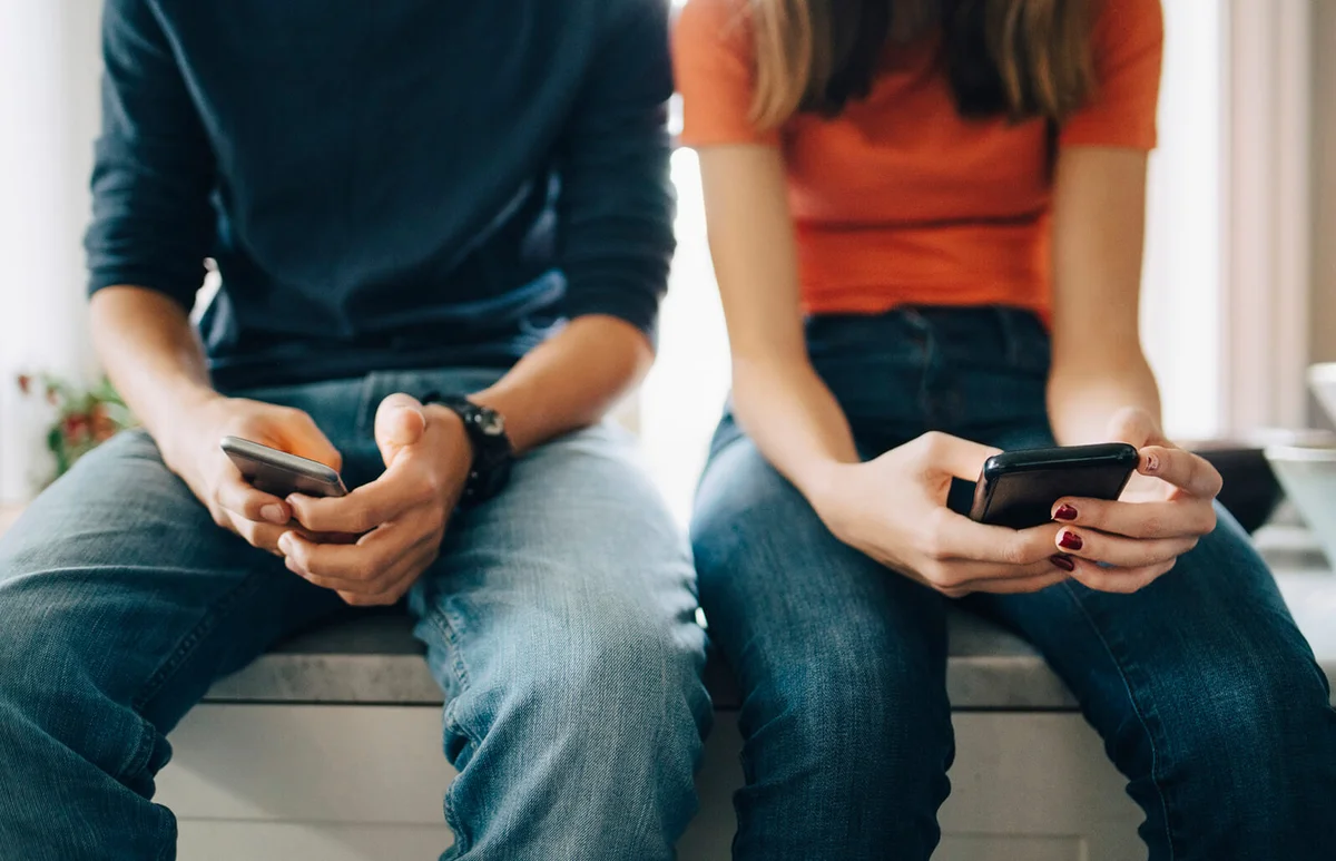 friends using mobile phones while sitting at kitchen counter