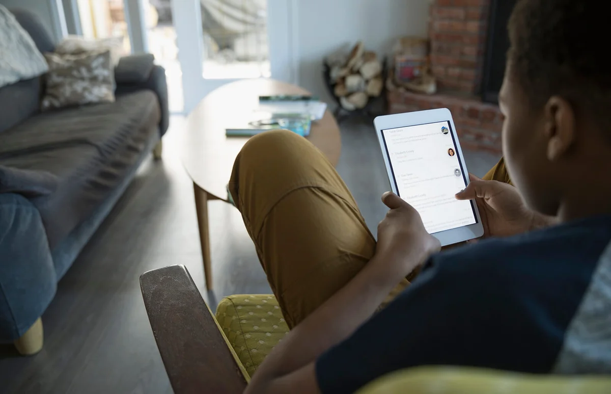 Teenage boy using digital tablet in living room