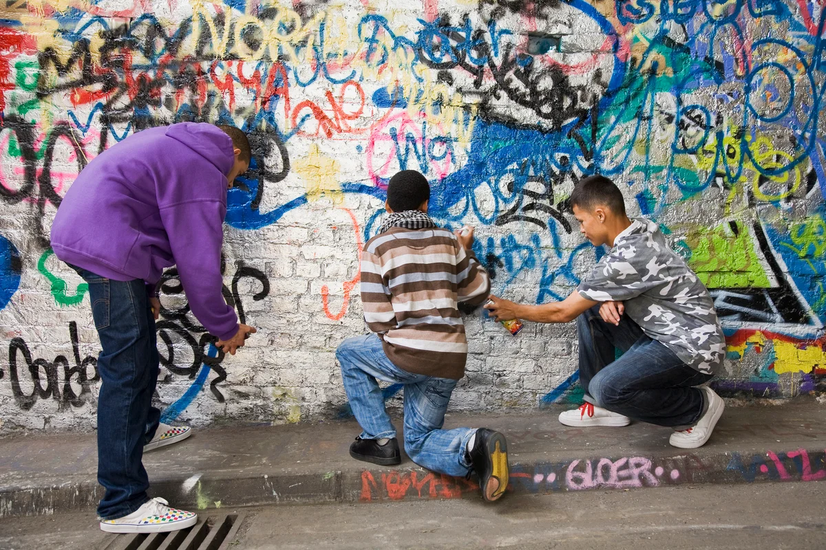 Teens spraying graffiti on wall