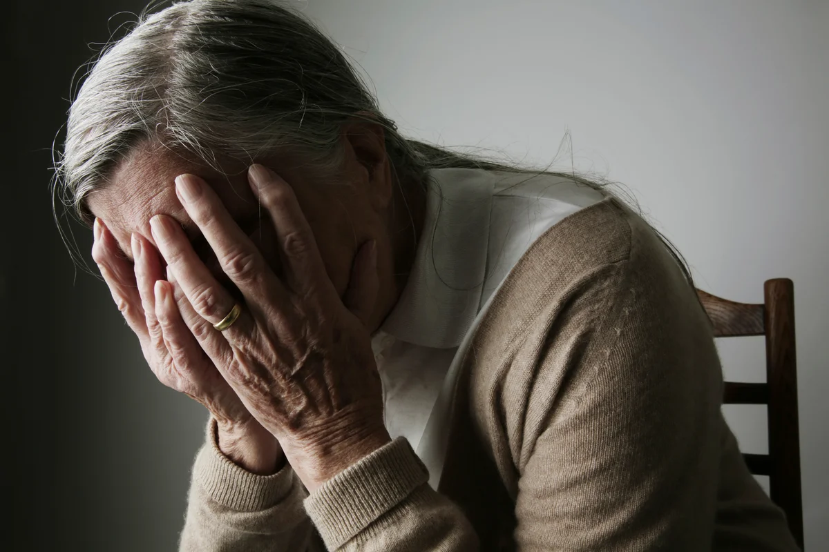 Woman holding head in hands