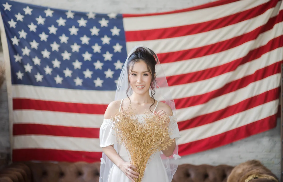 Bride Holding Bouquet Standing Against American Flag