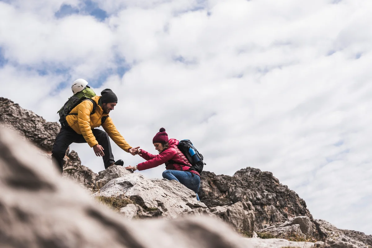 Man helping woman rock climbing