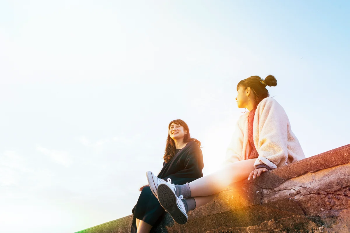 2 friends sitting on a wall