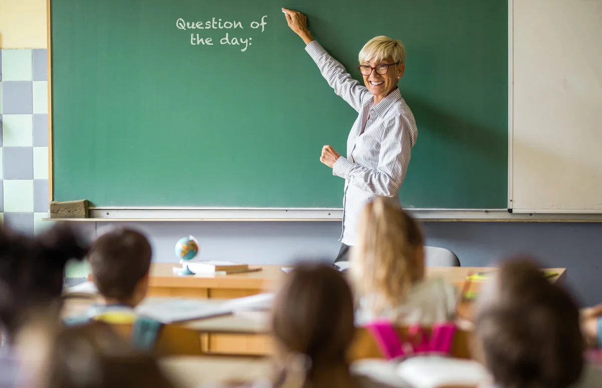 Teacher writing on blackboard at elementary school