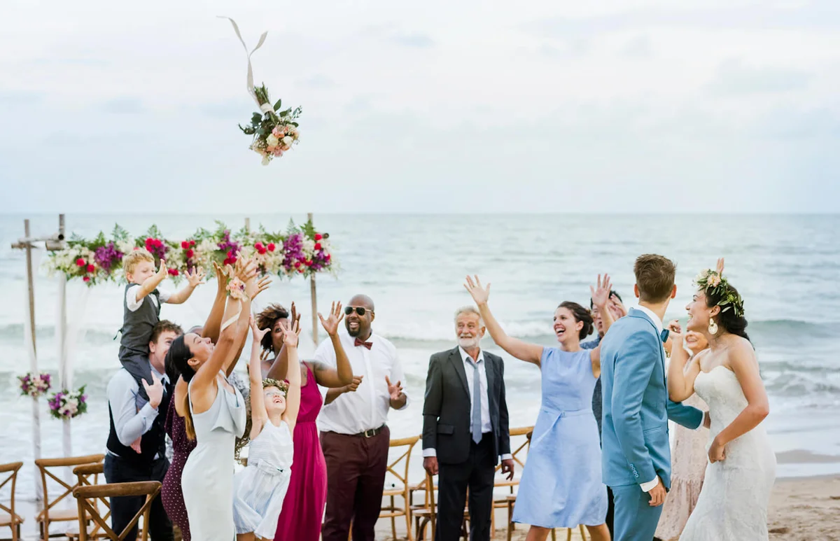 Bride throwing the bouquet at wedding on the beach