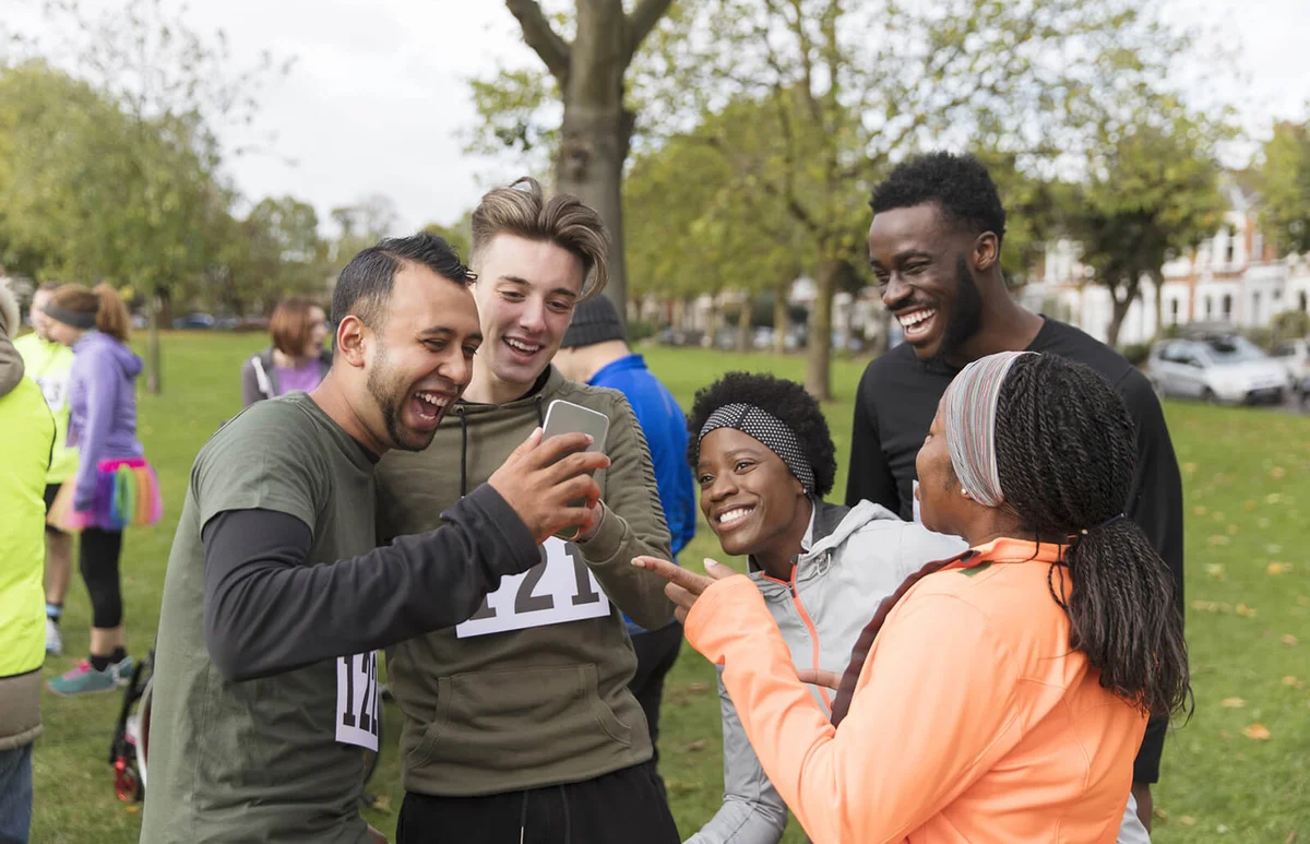Friend runners with smart phone at charity run in park