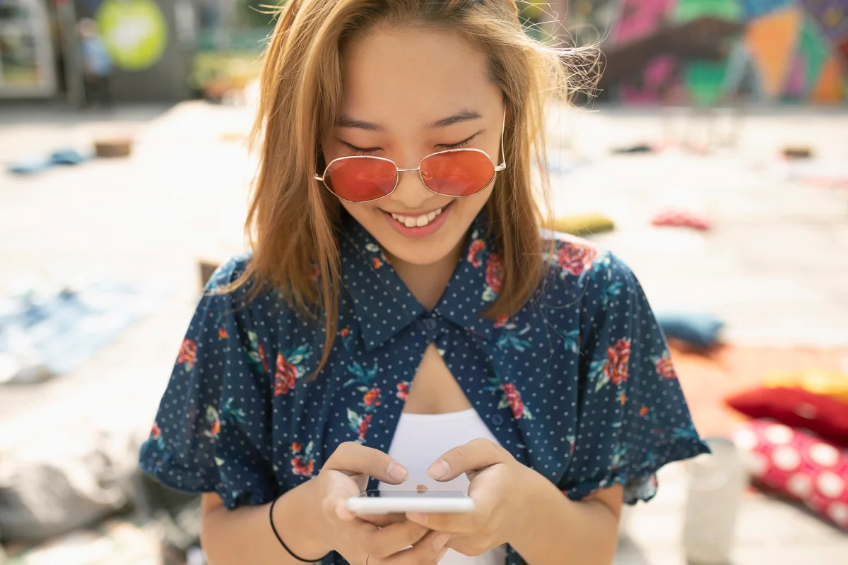 Teenage girl with sunglasses using smart phone