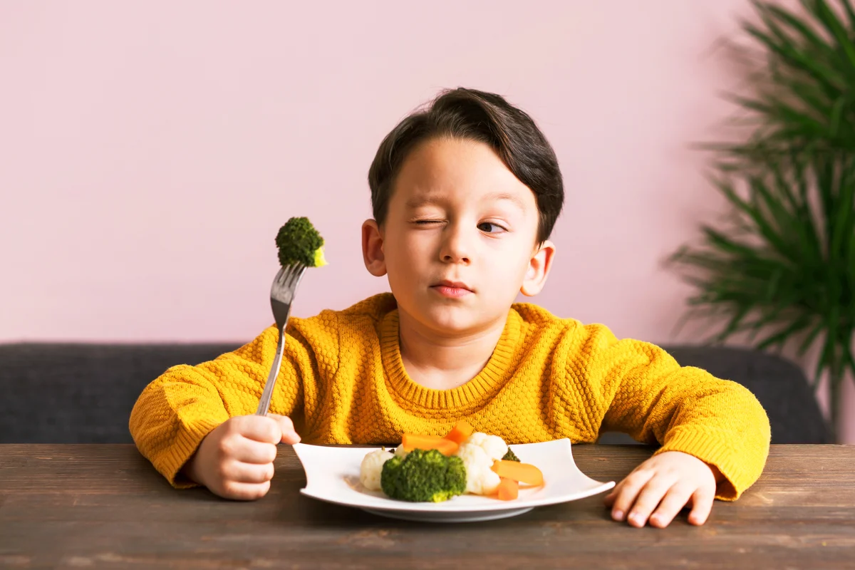 Kid eating a plate full of vegetables