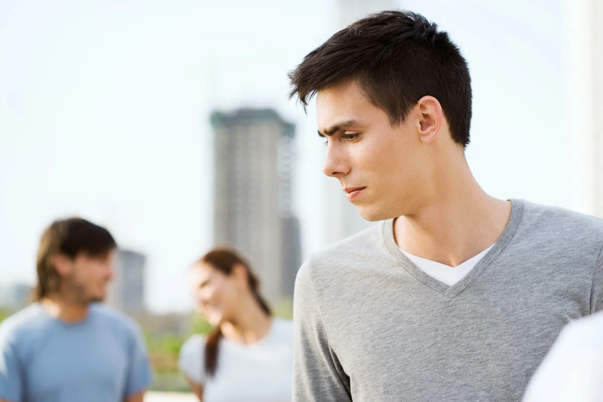 Young man looking to the side, young couple in background
