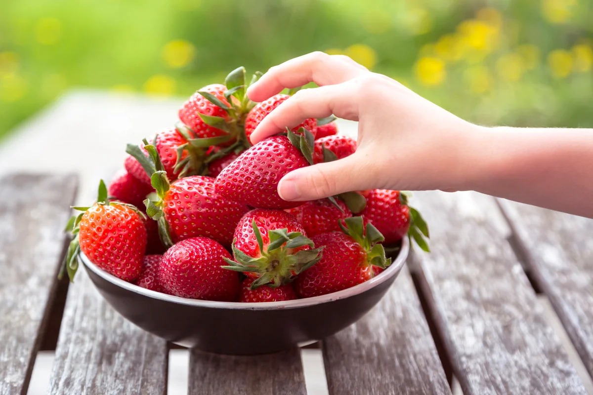 Girl's hand taking strawberry