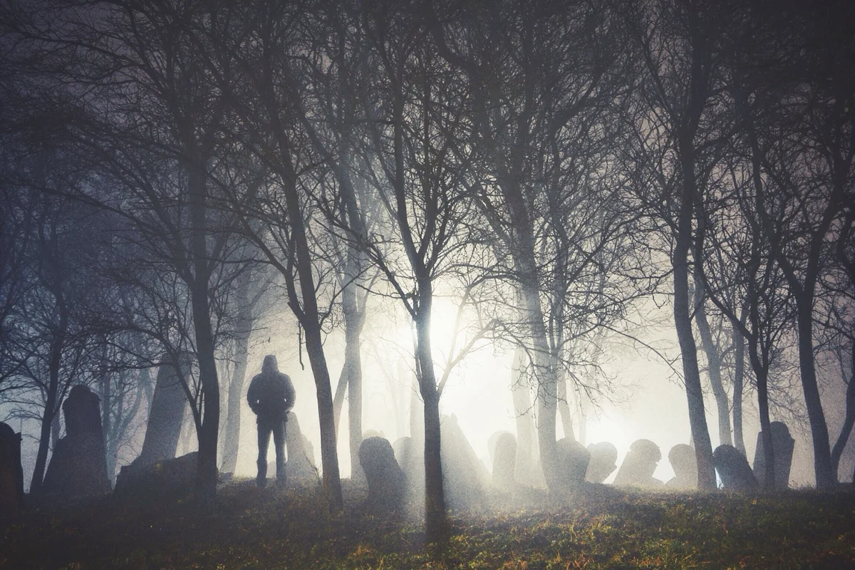 Man standing in a foggy graveyard