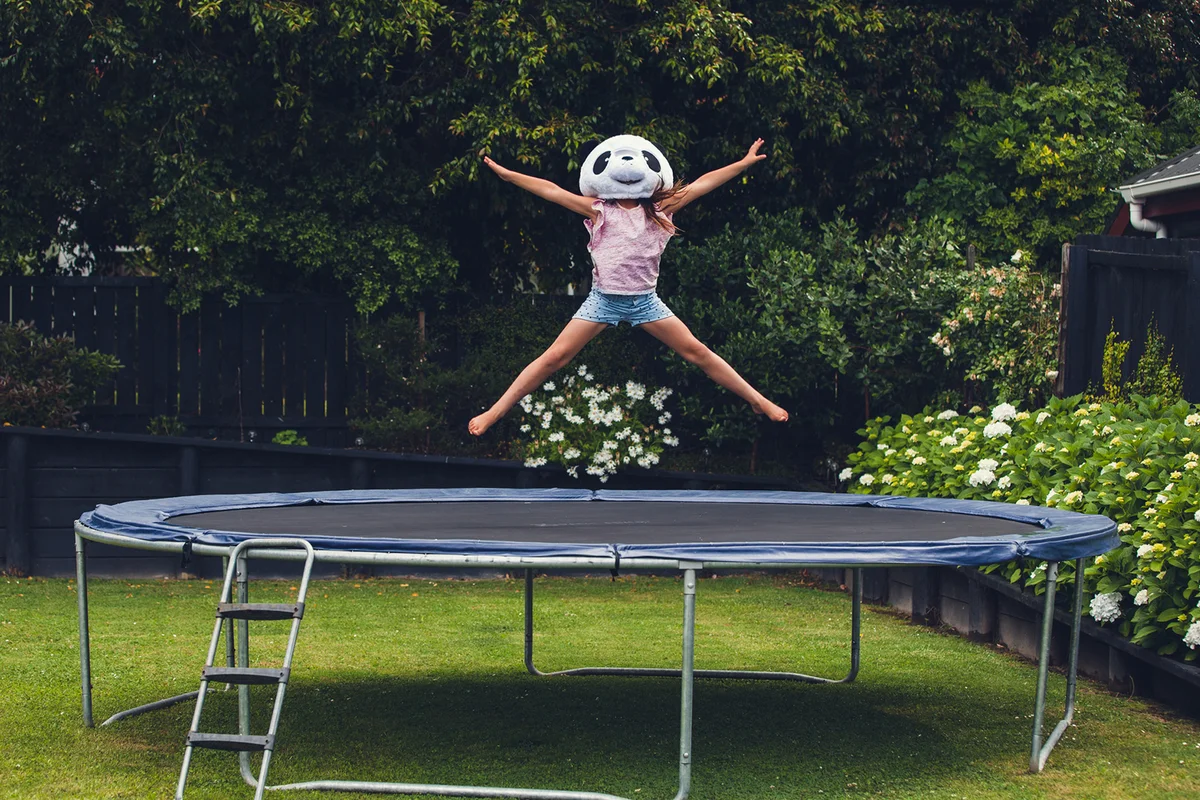 Girl on trampoline wearing panda mask
