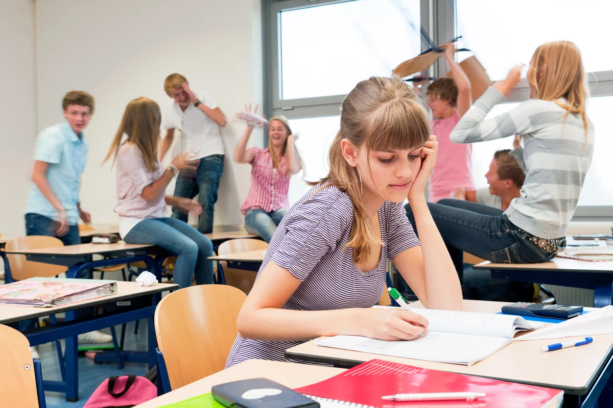 Sad high school girl in chaotic classroom