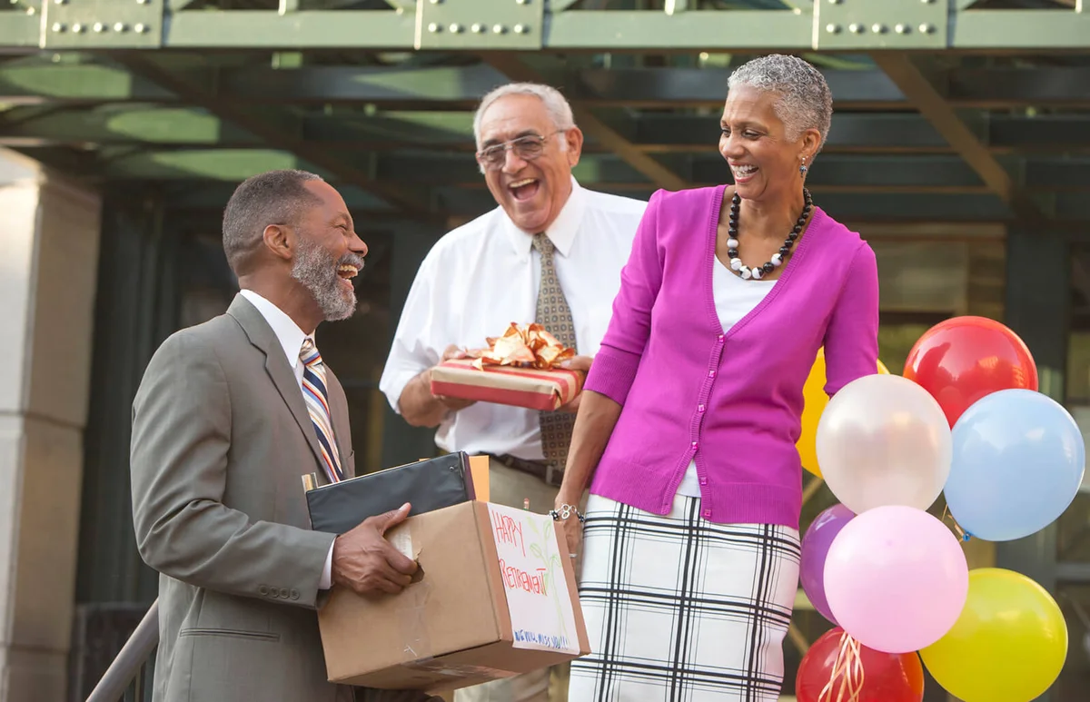 Co-workers celebrating with retiring man carrying belongings