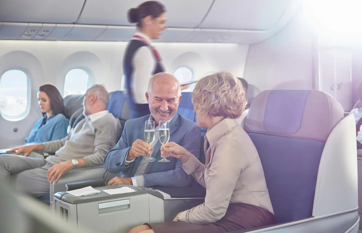 couple toasting champagne glasses in first class on airplane
