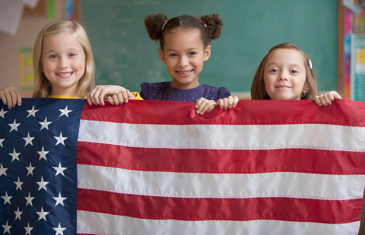 Students in classroom holding American flag