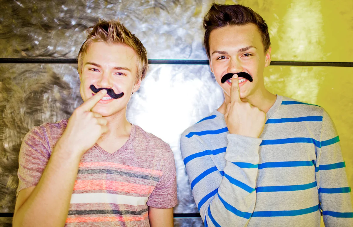 Two young men wearing fake mustaches