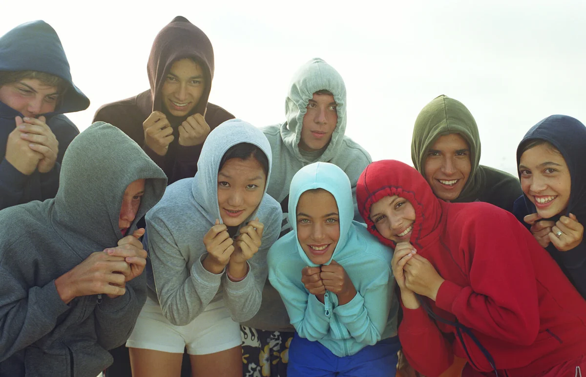 Group of teens wearing hooded sweatshirts on beach