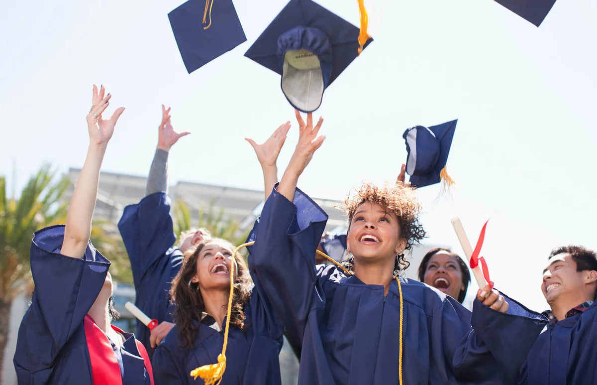 Graduates tossing caps into the air