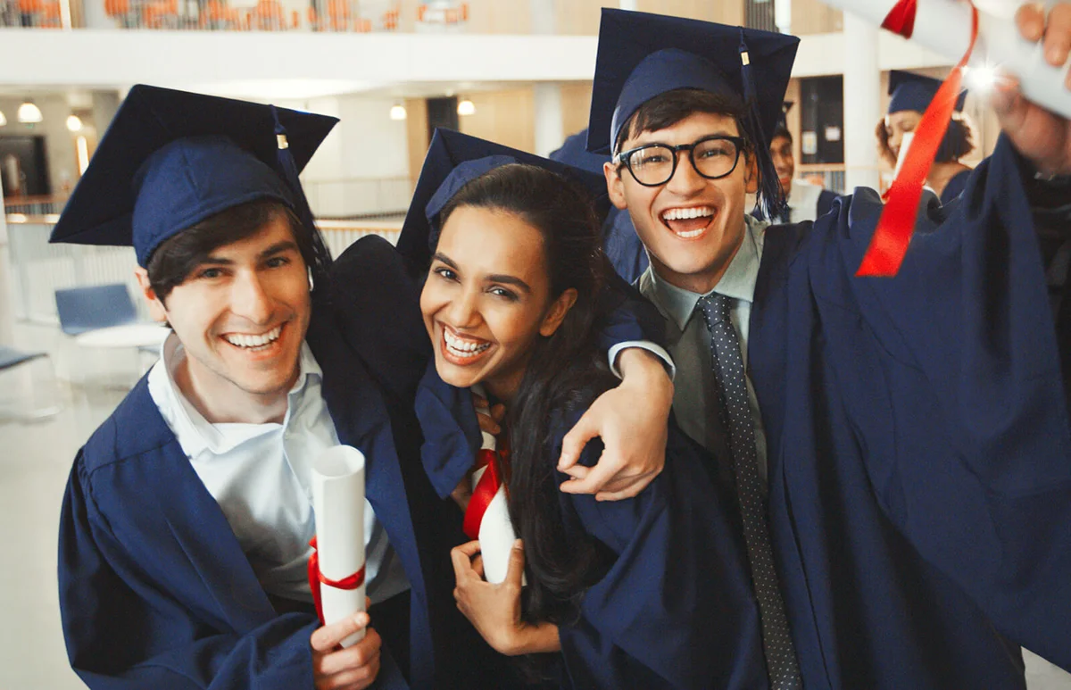 Portrait enthusiastic graduates in cap and gown with diplomas