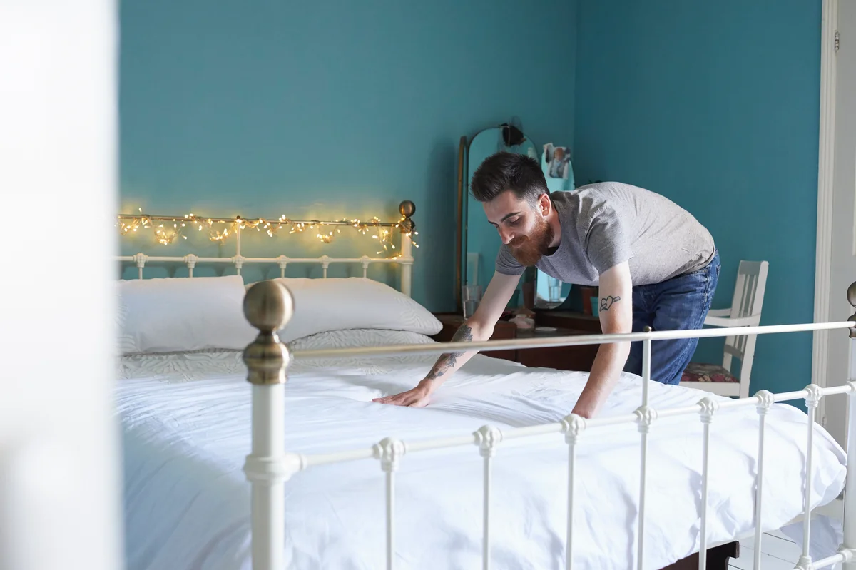 Young man making his bed