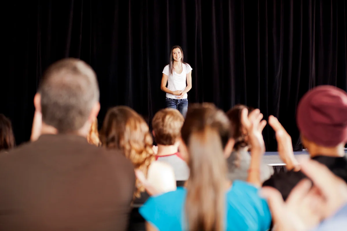 Audience clapping for a teenage girl on stage