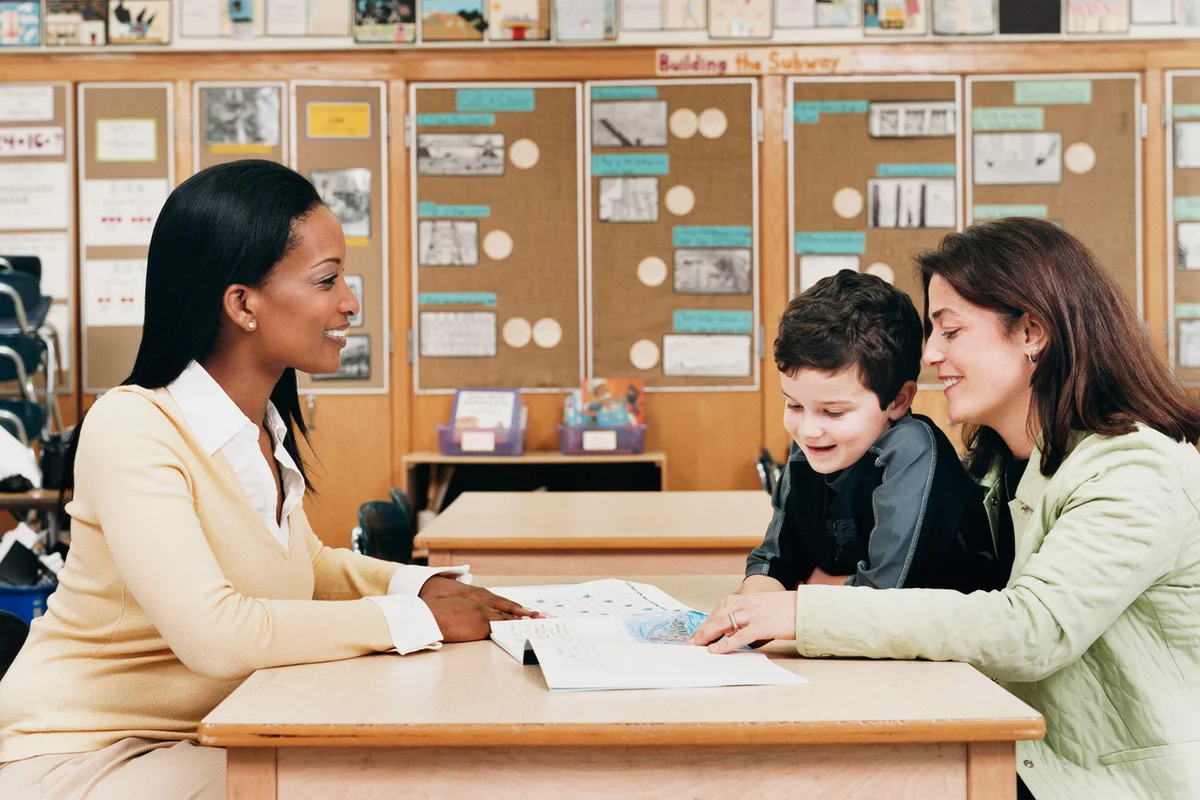 Teacher showing book to parent and her son