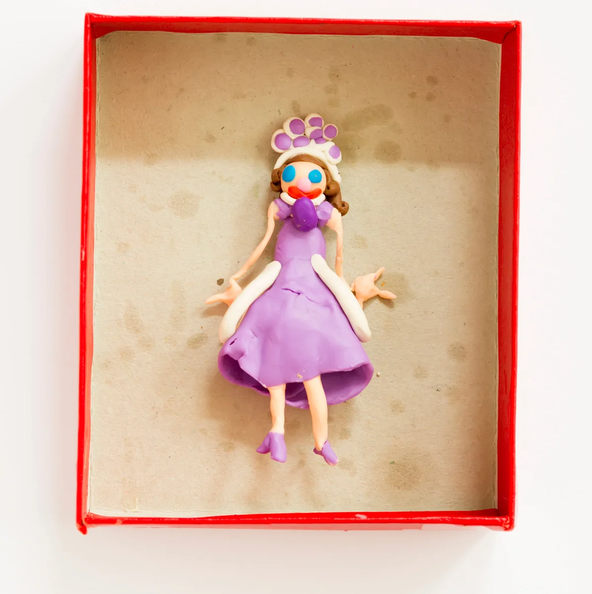 Clay doll sculpture in cardboard box