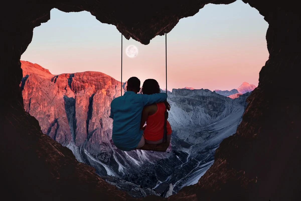 Couple on swing contemplating the mountains in a romantic view with heart shape