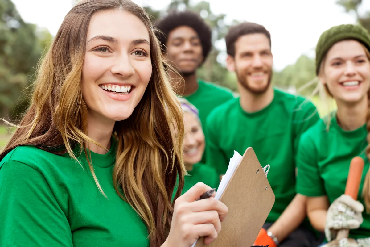 Environmentalist holding clipboard with volunteers in background