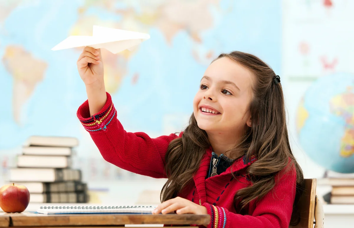 Little girl looking at paper airplane