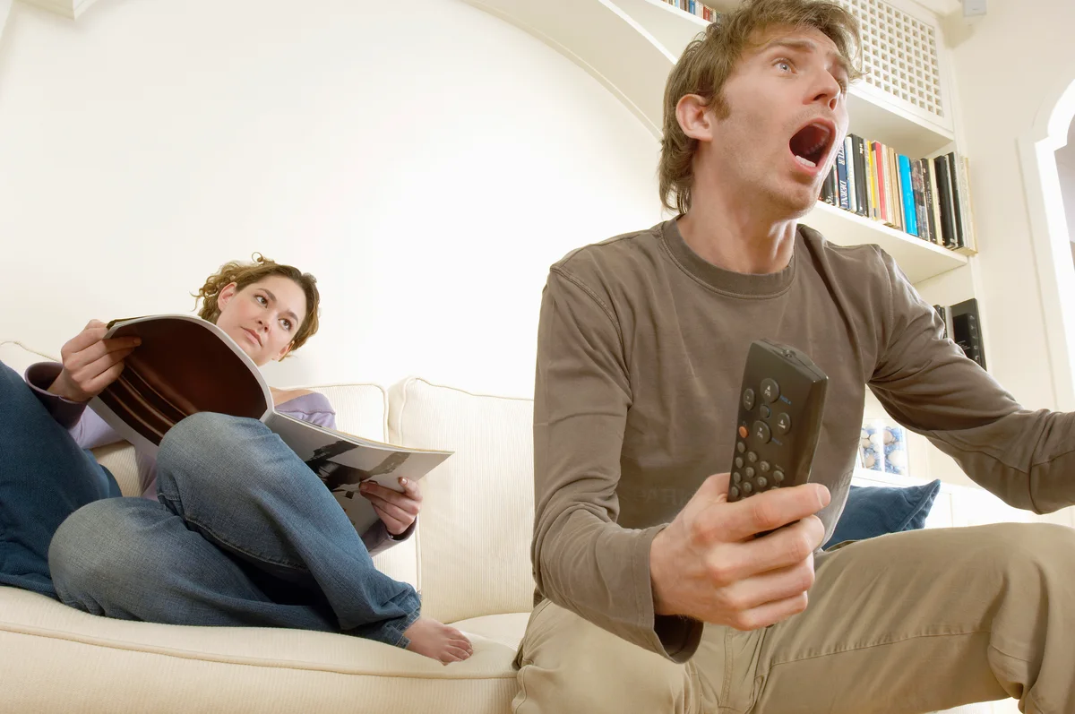 Woman reading and man watching sports