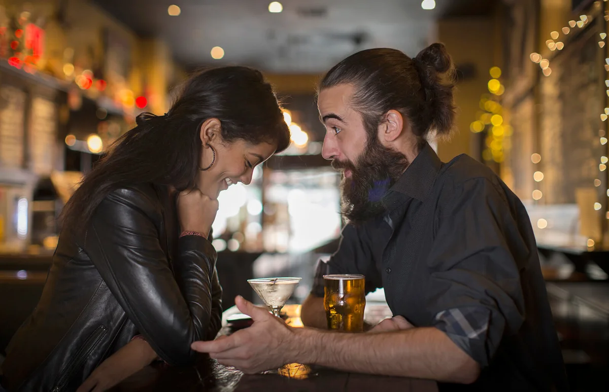 Young couple talking at table with cocktail and beer