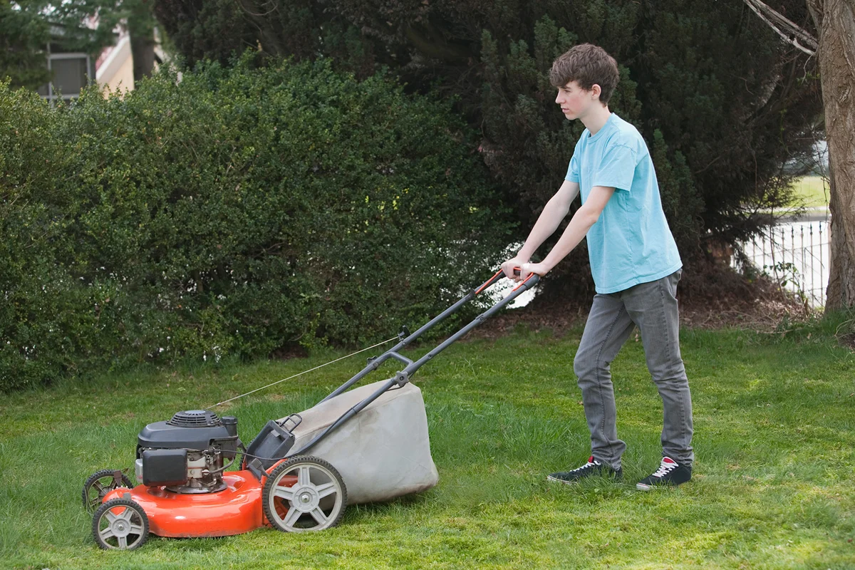 Teen boy mowing lawn