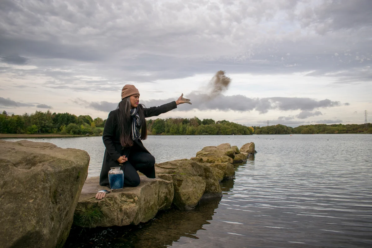 Woman scattering ashes over the water