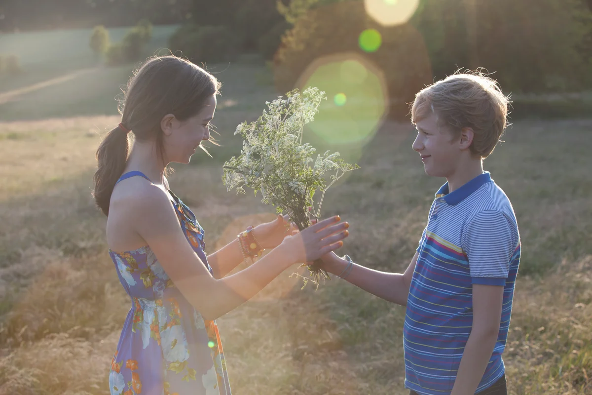 Young teen boy giving a girl flowers