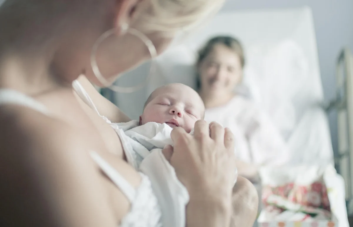 Newborn infant being gently held in arms of aunt