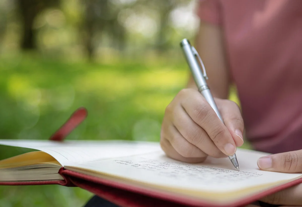 writing on notebook in park